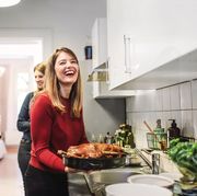 young woman smiling and holding christmas poultry in kitchen