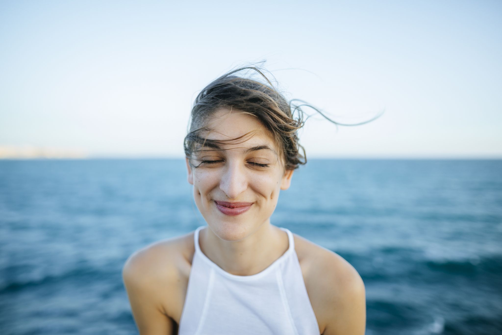 Young woman smiling with eyes closed with sea background