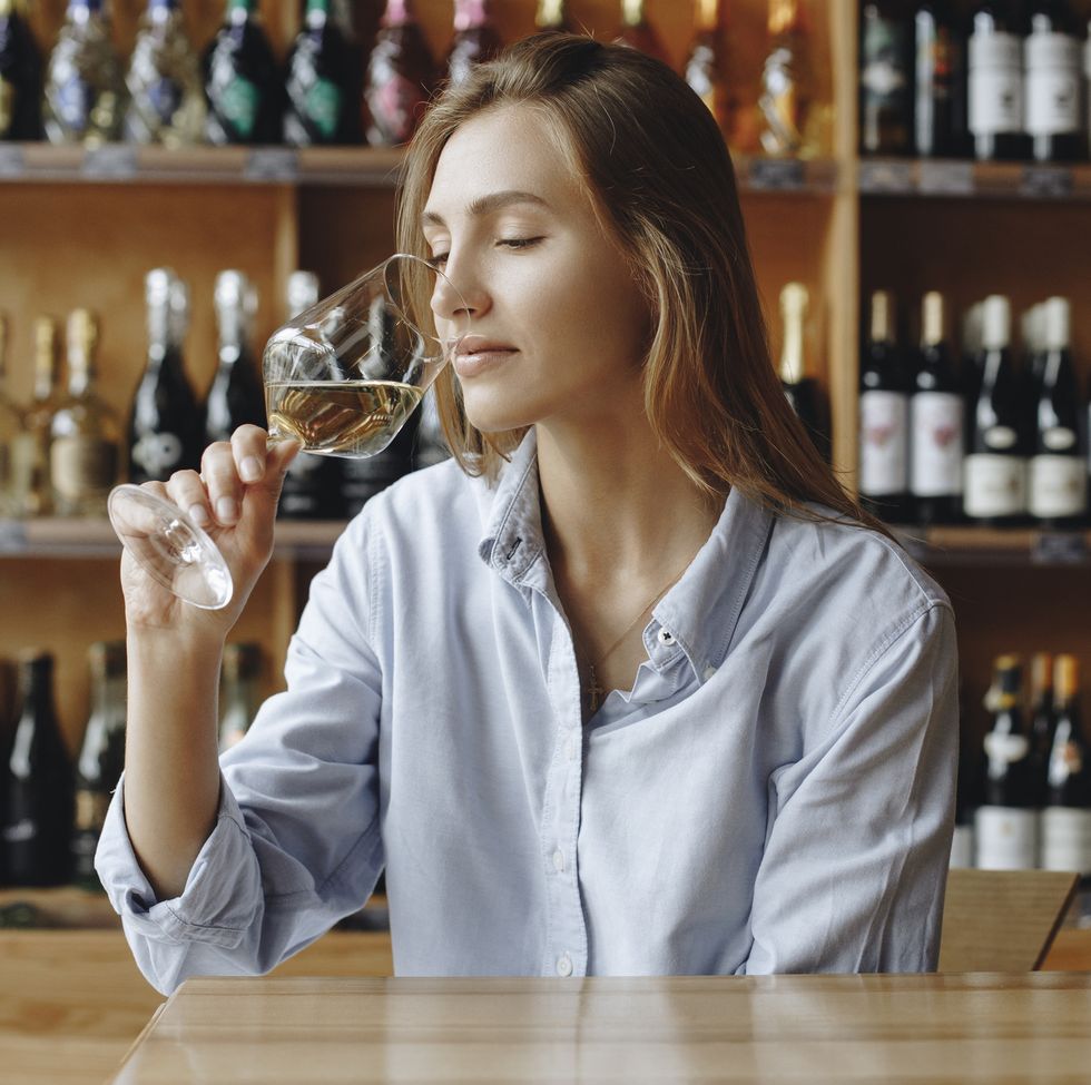 young woman sniffing glass of white wine