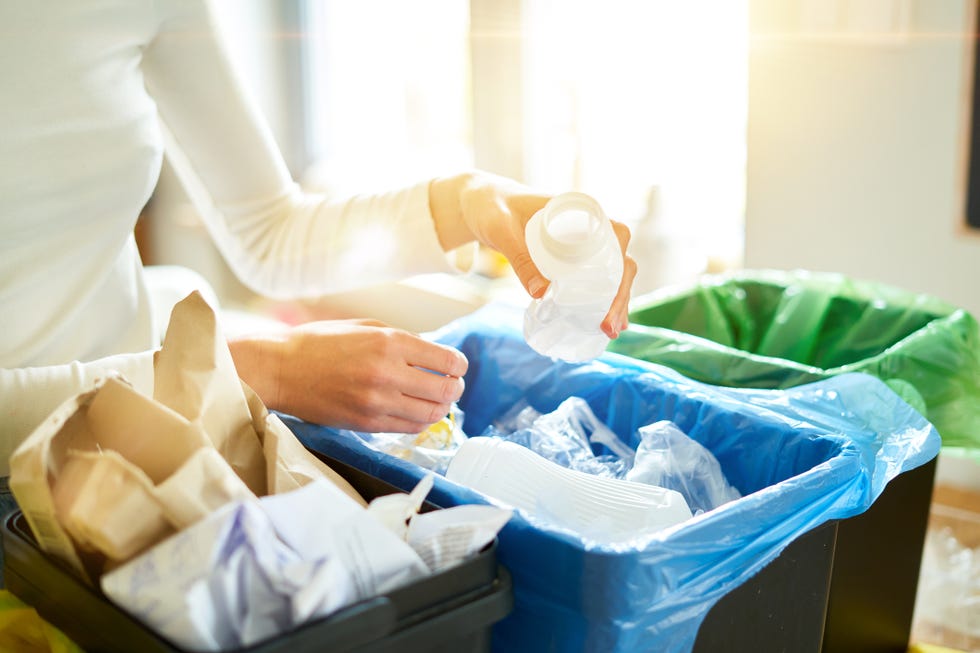 una chica joven elige, para reciclaje, los deshechos de su casa