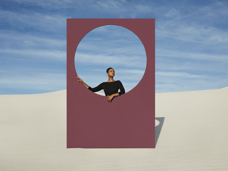 young woman standing by window frame at white desert