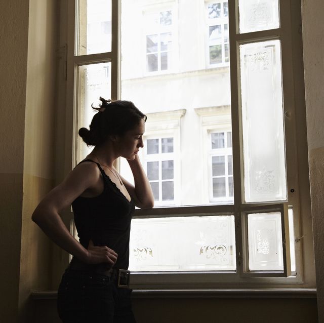 young woman standing in a stairway looking outside the window