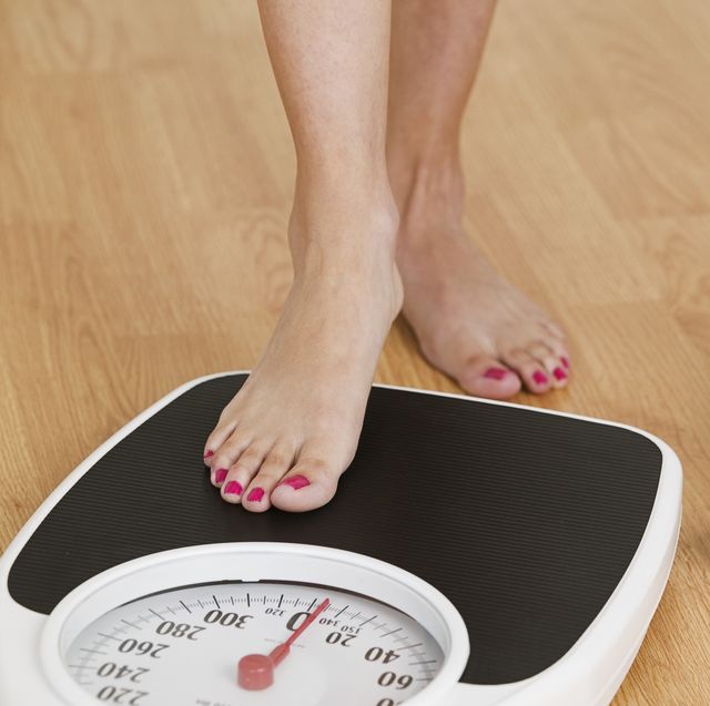 young woman stepping on a weighing scale