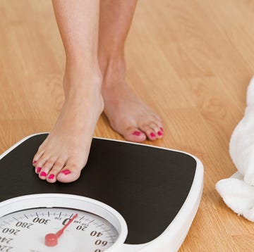 young woman stepping on a weighing scale