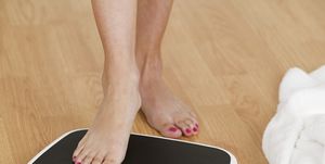 young woman stepping on a weighing scale