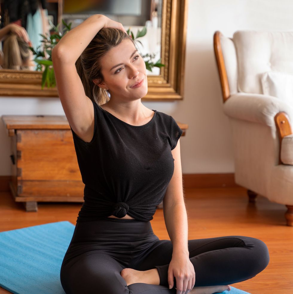 young woman stretching her neck before exercising at home