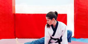 Young woman stretching in a dojo wearing taekwondo suit