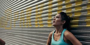 Young woman taking a break from running, against shutter