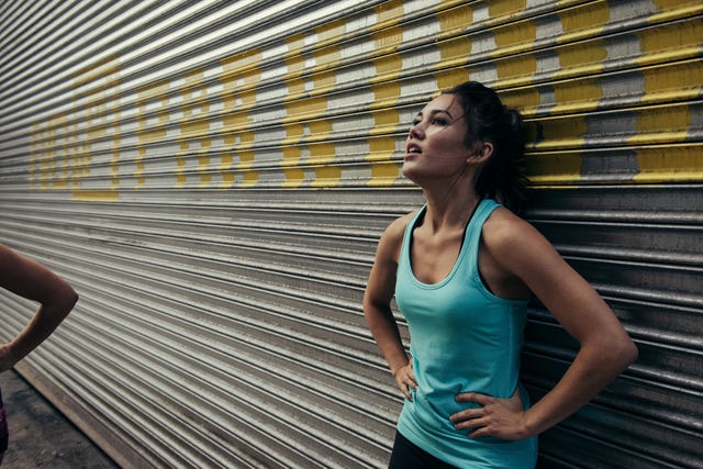 young woman taking a break from running, against shutter