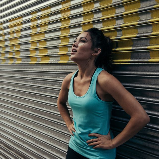 young woman taking a break from running, against shutter