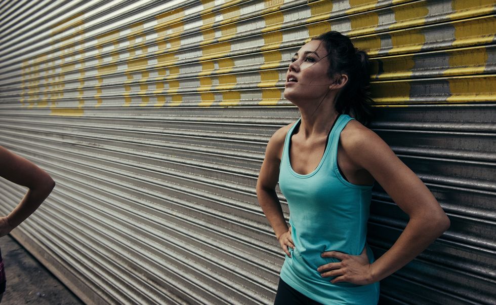 young woman taking a break from running, against shutter