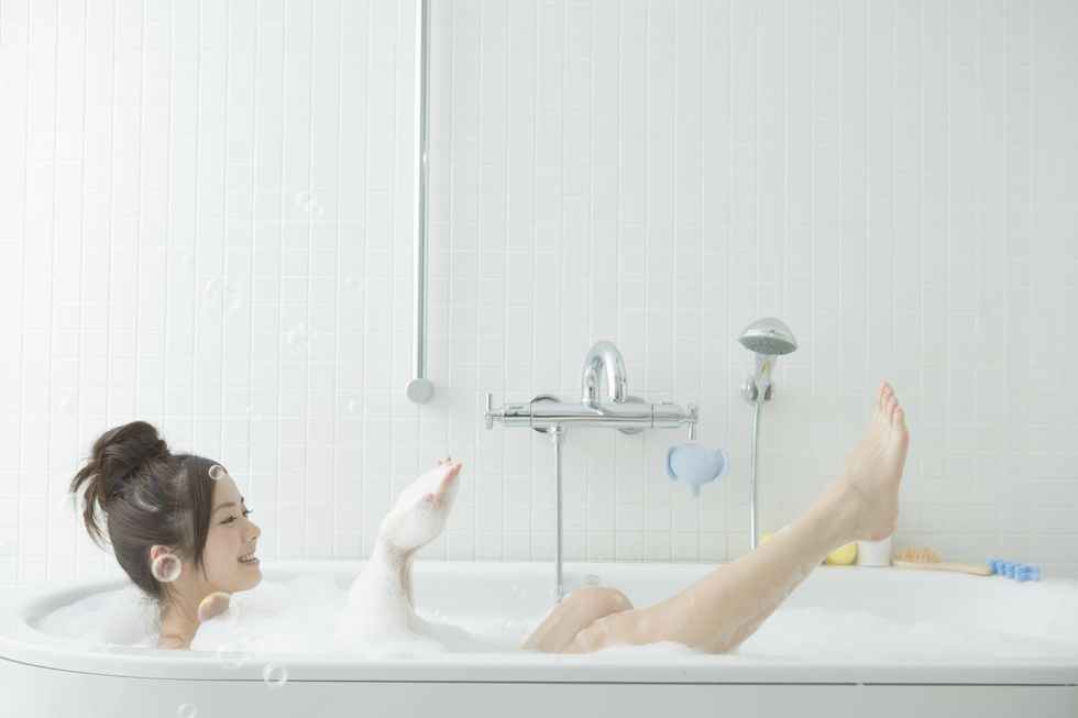 young woman taking a bubble bath, scooping bubble