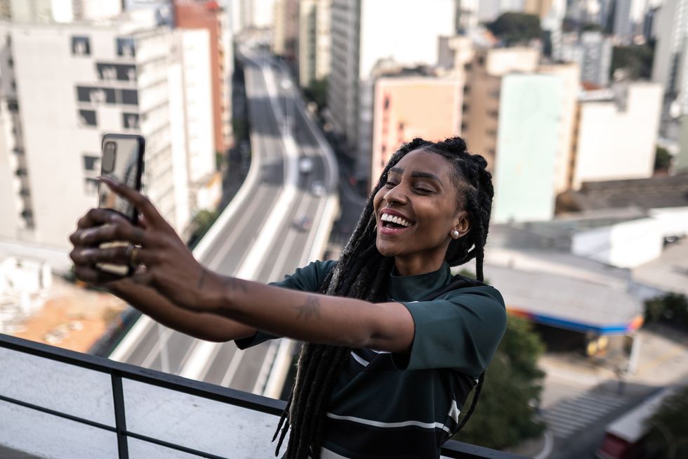 young woman taking selfie or doing a video call on apartment's balcony