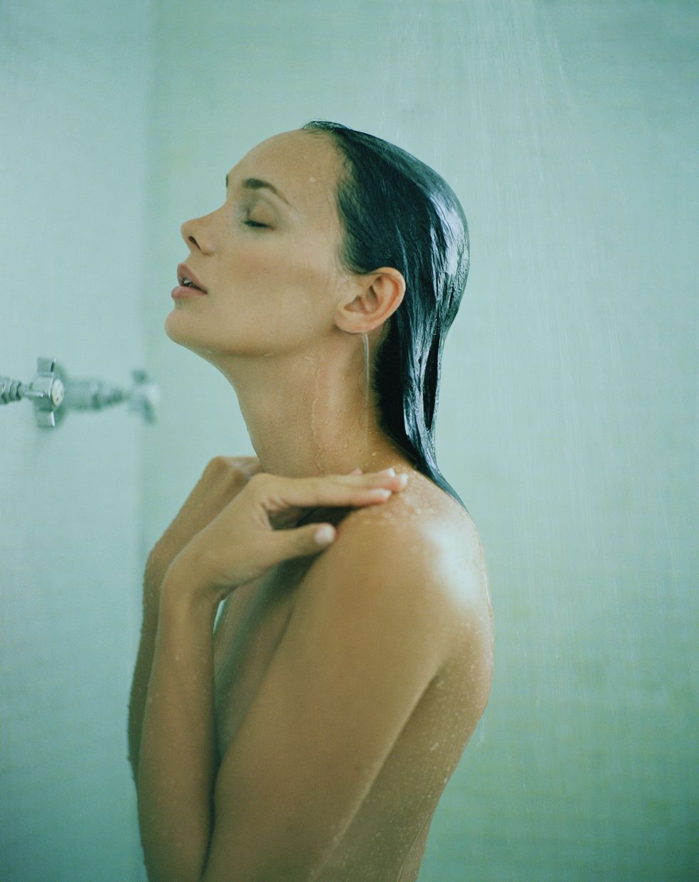 Young woman taking shower, side view