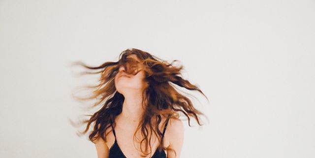 Young Woman Tossing Hair Against White Background
