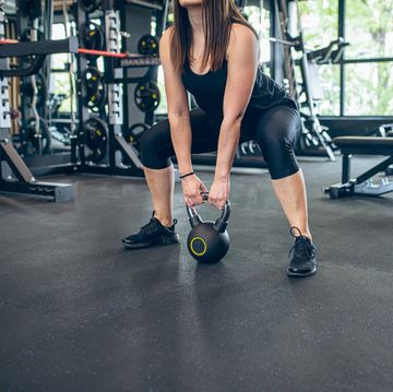 young woman training in gym with kettlebell