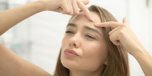 Young woman troubled checking wrinkles on her forehead