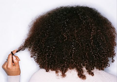 young woman twisting hair round finger, rear view
