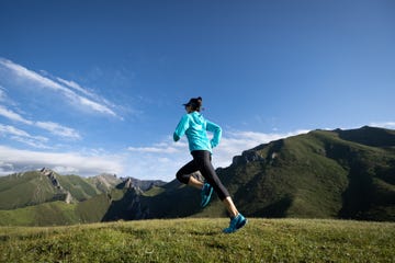 young woman ultramarathon runner running at mountain top