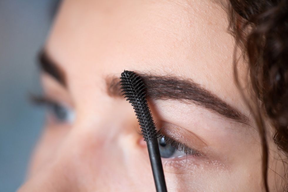 Young woman undergoing eyebrow correction procedure. Eyebrow Mascara