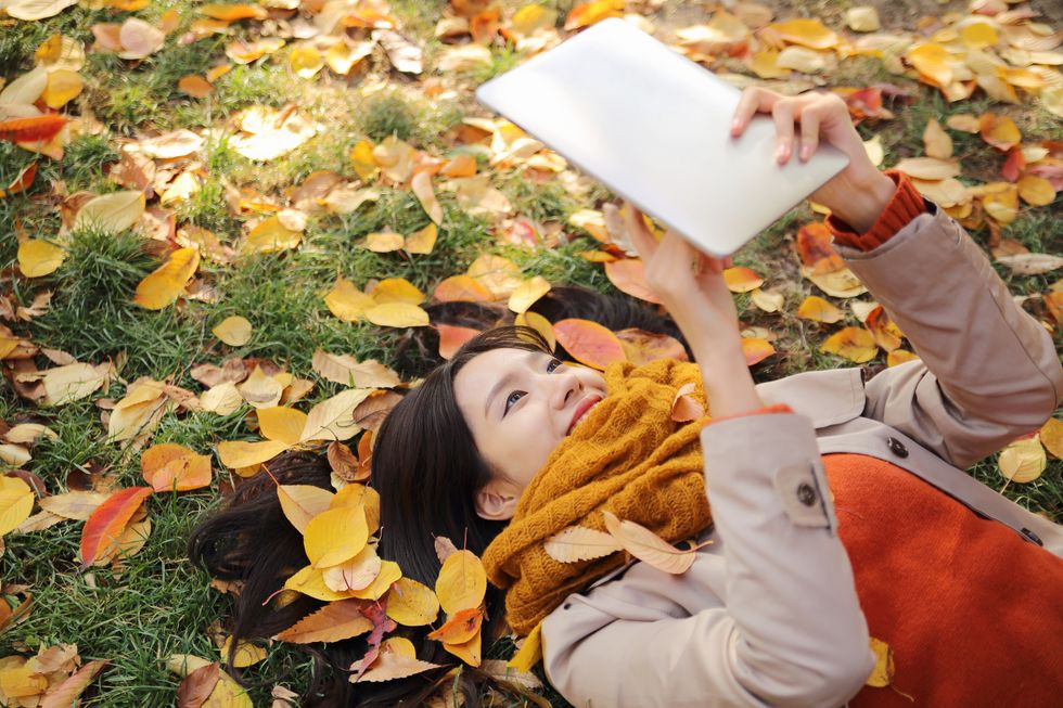 young woman using digital tablet in autumn park