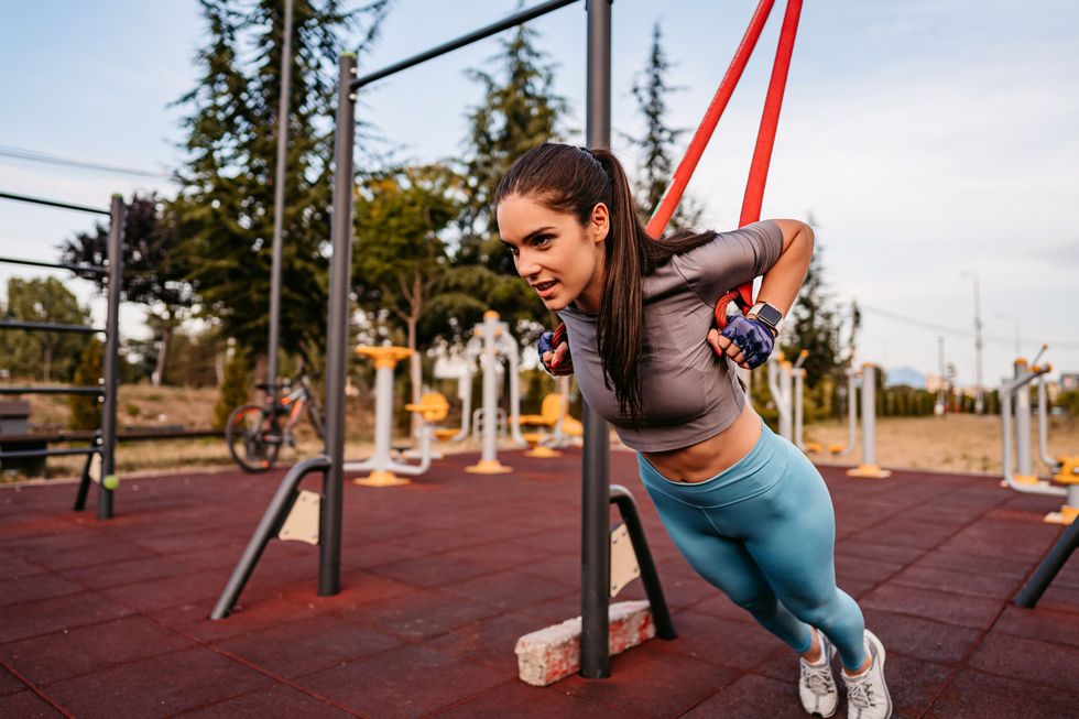 young woman using expander working out outdoor