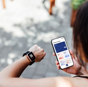 young woman using fitness tracker app on smart watch and smartphone