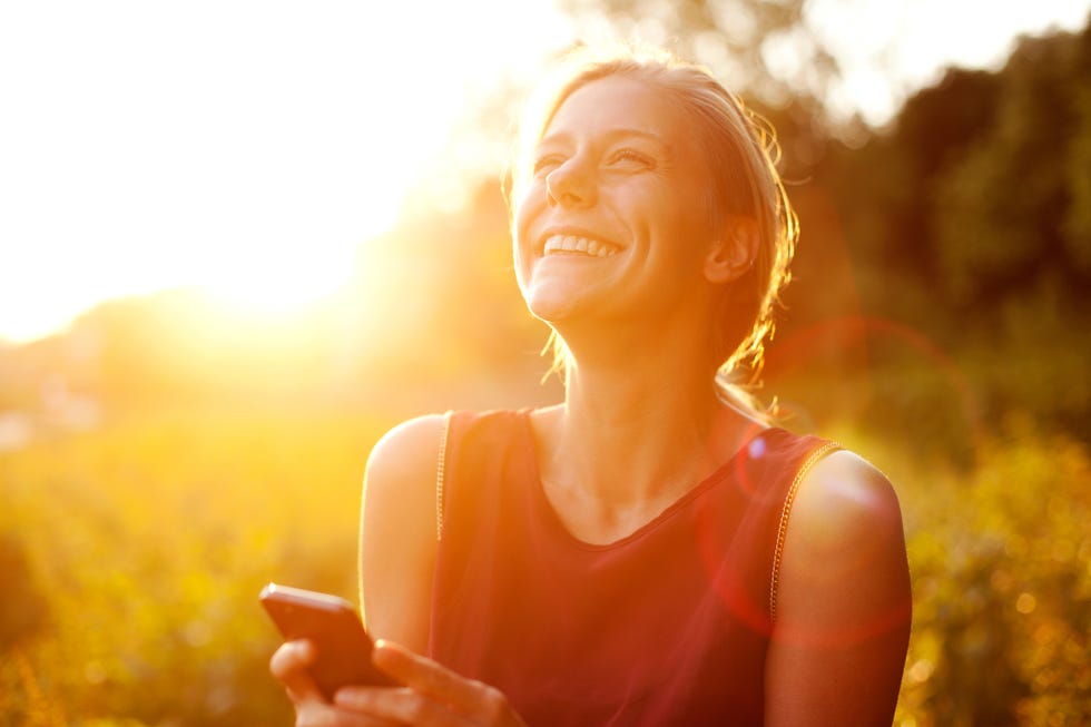 young woman using smart phone at sunset