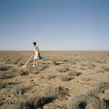 young woman vacuming in desert, side view