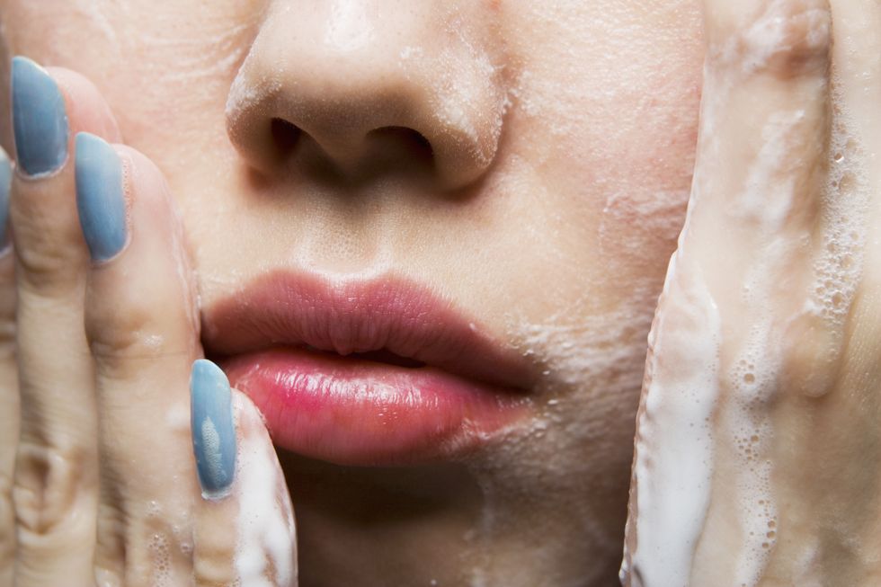 Young woman washing face, close-up of mouth