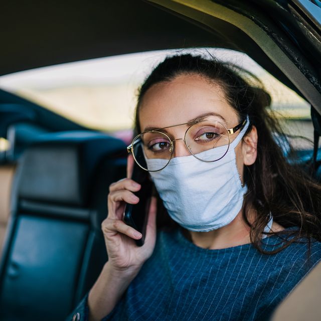 covid 19, young woman wearing disposable face mask while driving