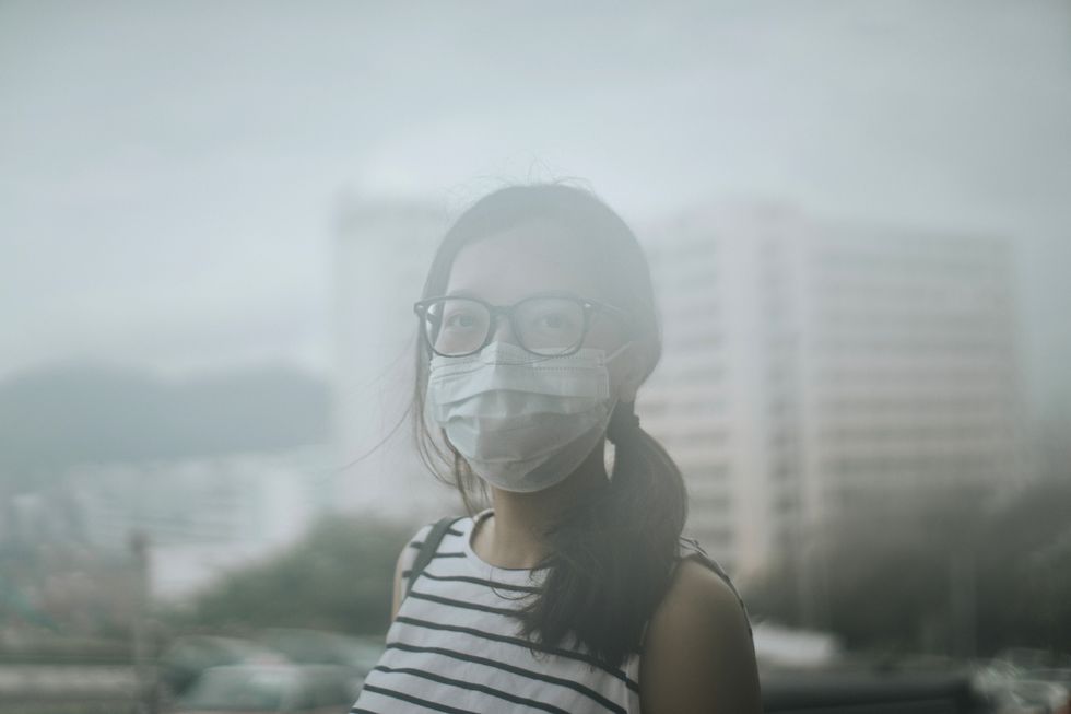Young woman wearing protective face mask outdoors due to the polluted air