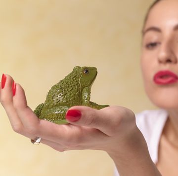 young woman wishing kissing frog