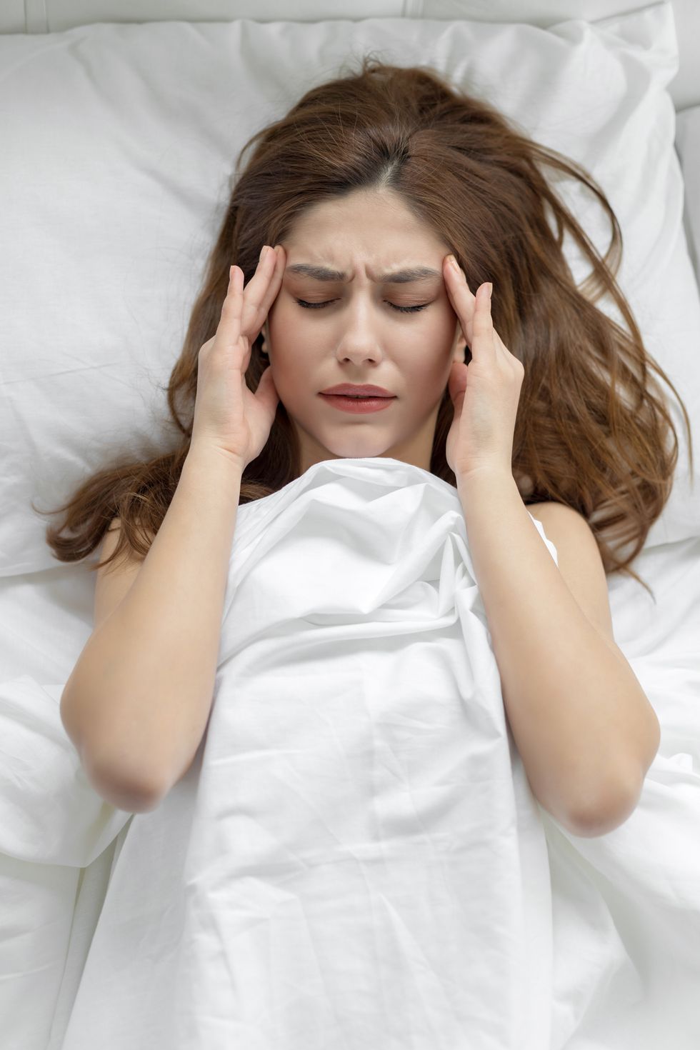 young woman with a migraine on bed
