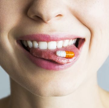 young woman with capsule on her tongue, smiling