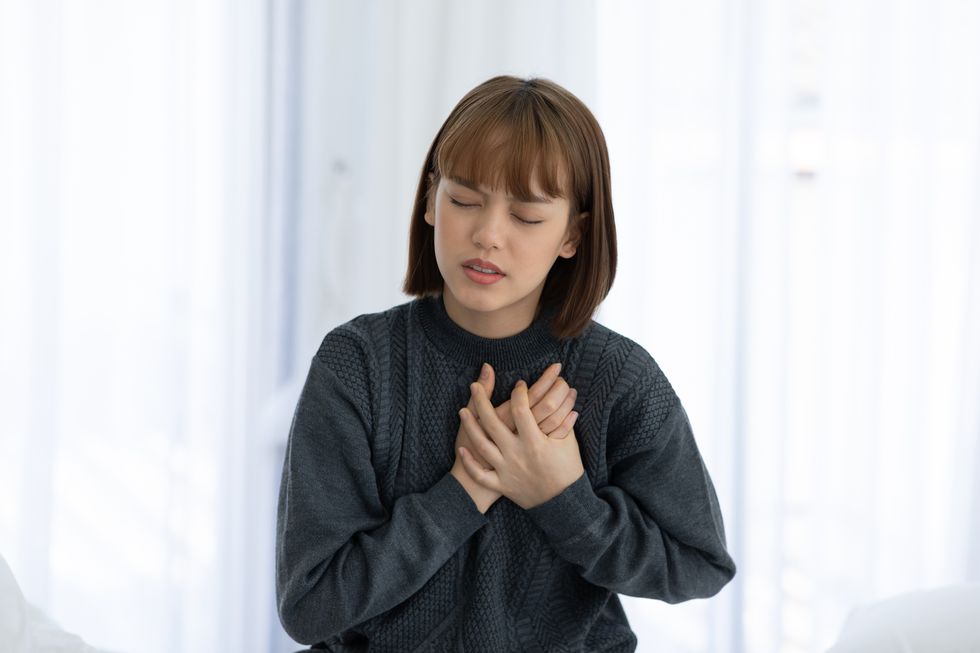 Young Woman With Chest Pain Standing At Home