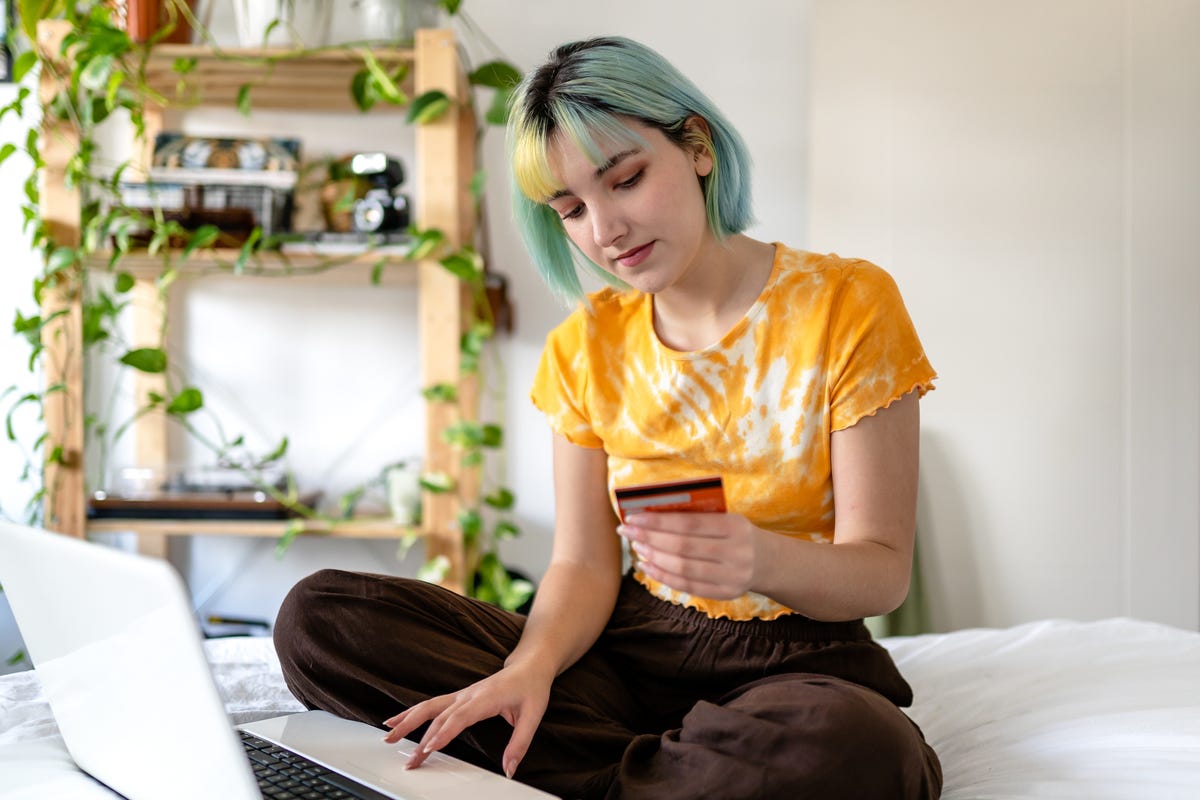 young woman with colored hair is shopping online with a credit card