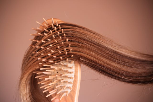 young woman with comb brushing her blonde hair