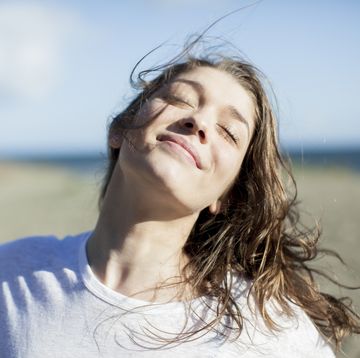 jonge vrouw lacht op strand met ogen dicht