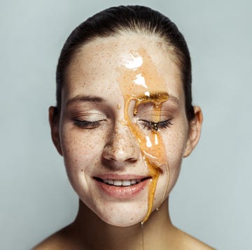 young woman with freckles and honey on face with closed eyes, posing toothy smile and happy face