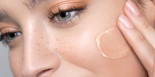 Young woman with perfect skin applying foundation