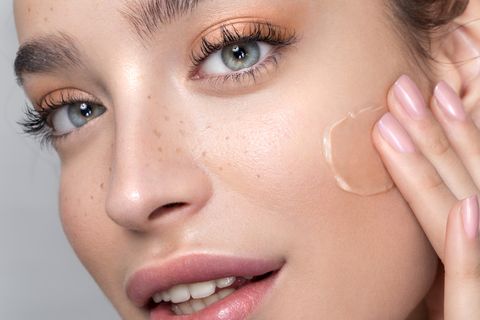 young woman with perfect skin applying foundation