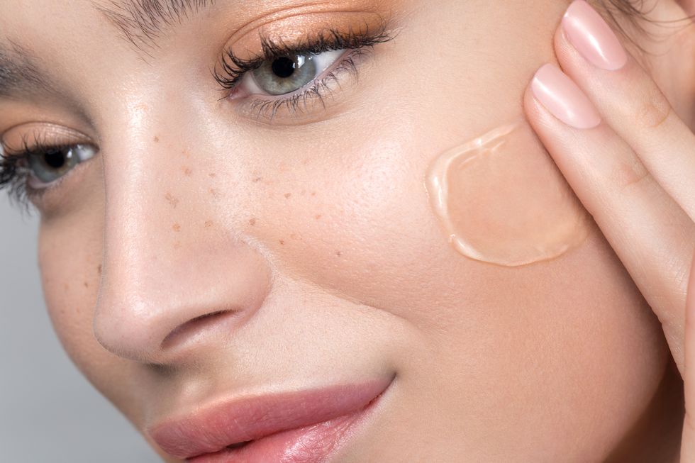 young woman with perfect skin applying foundation