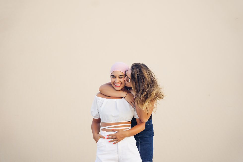 young woman with pink headscarf fighting cancer together with her friend