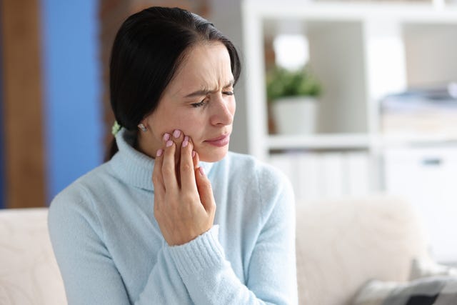 young woman with severe toothache at home