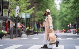 young woman with shopping bags walking on road