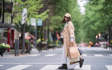 young woman with shopping bags walking on road