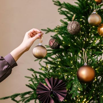 young woman's hand decorating christmas tree indoors