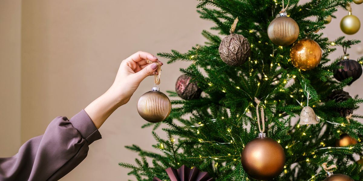 young woman's hand decorating christmas tree indoors