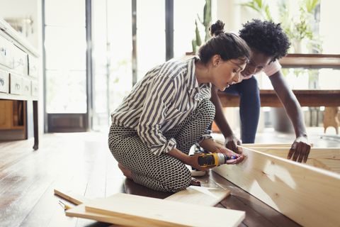 Young women assembling furniture with power drill